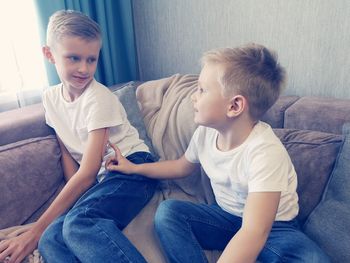 Smiling sibling sitting on sofa at home