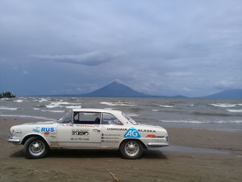 Vintage car on beach against sky