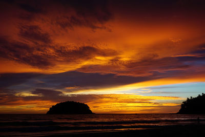 Scenic view of sea against dramatic sky during sunset