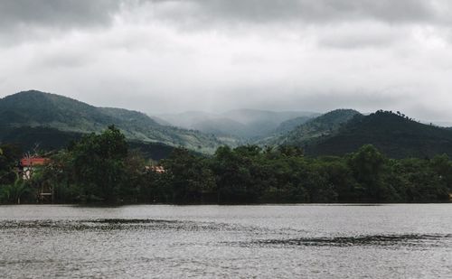 Scenic view of river by mountains against sky