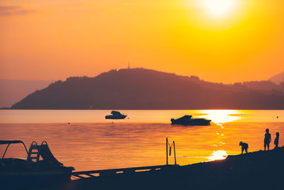 Silhouette boats in sea against orange sky