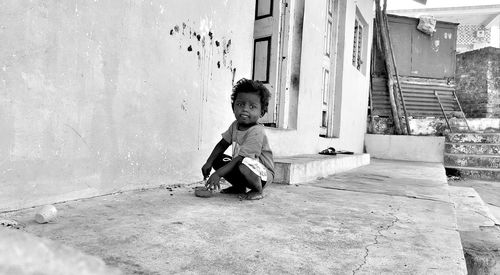 Portrait of boy crouching outside house