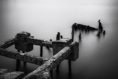 Old wooden post by sea against sky