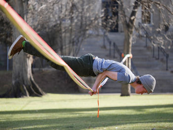 Full length of man performing stunt on rope over field