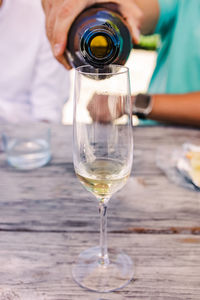 Close-up of man's hand pouring sparkling wine or champagne into the glass. summer party