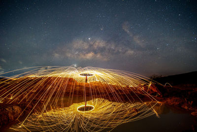 Man spinning wire wool against star field at night