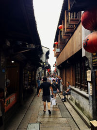 Rear view of people walking on street amidst buildings