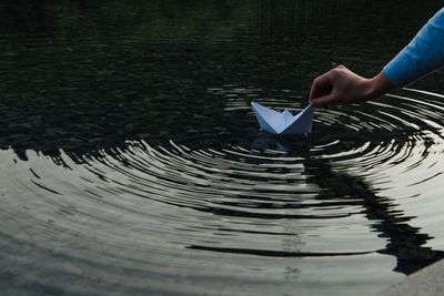 Midsection of man holding paper in lake