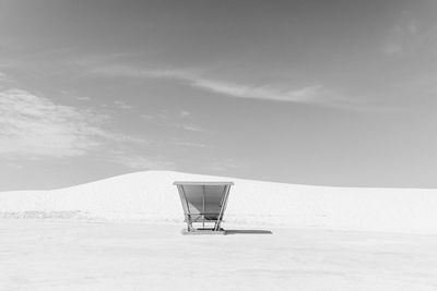 Shopping cart on beach against sky