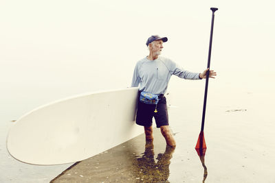 Portrait of a mature man and his paddle board after a paddling trip