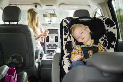 Brother sleeping while sister playing in car