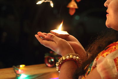 Midsection of woman holding lit diya