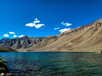 Scenic view of sea and mountains against blue sky