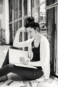 Woman looking at book while sitting by window