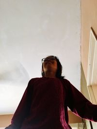 Low angle view of woman looking away against wall