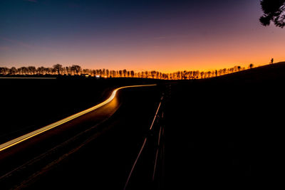 Light trails on road against sky during sunset