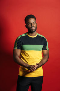 Portrait of young man standing against red background