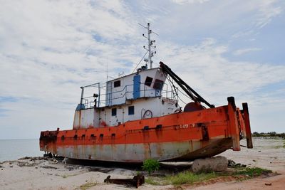 Abandoned boat on beach against sky