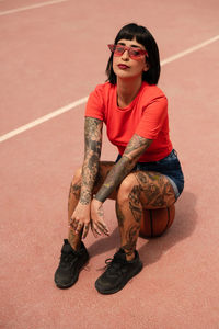 Caucasian girl with tattoos and short black hair on a sports court