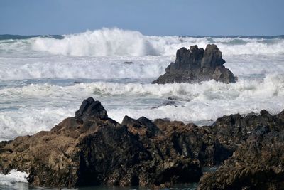 Scenic view of rocks in sea against sky