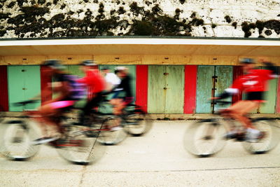 Blurred motion of people riding bicycle on street