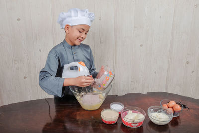 Boy mixing flour and egg yolk in bowl