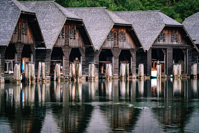 Wooden posts in lake against buildings