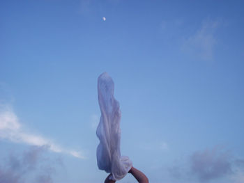 Cropped hands of person holding textile against sky