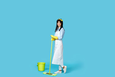 Portrait of female doctor standing against blue background