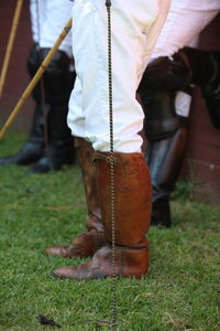 Low section of polo players standing on grassy field