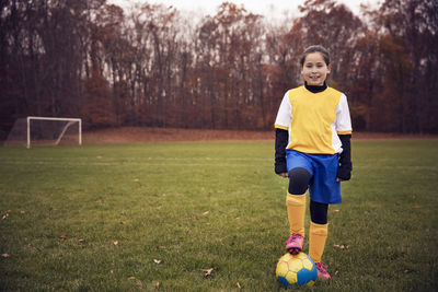 Confident player standing with soccer ball on playing field