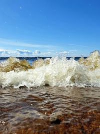 Waves splashing on shore against sky