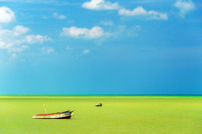Scenic view of green sea against blue sky