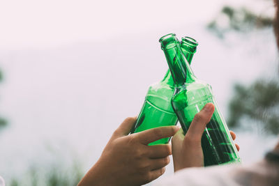 Close-up of hand holding bottle against white background