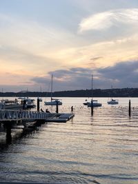 Boats moored at harbor against sky during sunset