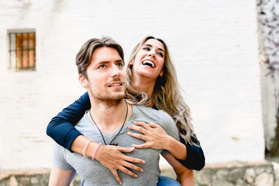 Boyfriend carrying girlfriend piggyback against wall