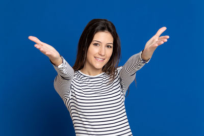 Portrait of young woman standing against blue background