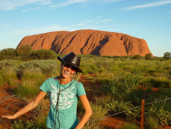 Young woman wearing hat standing on land against sky