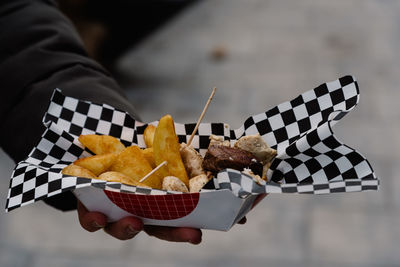 Cropped image of woman hand holding meat with french fries