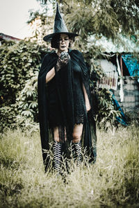 Portrait of woman standing by plants on field