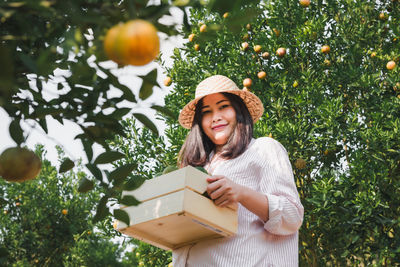 Portrait of smiling young woman standing against trees