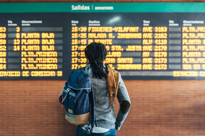 Rear view of man reading airport departure board