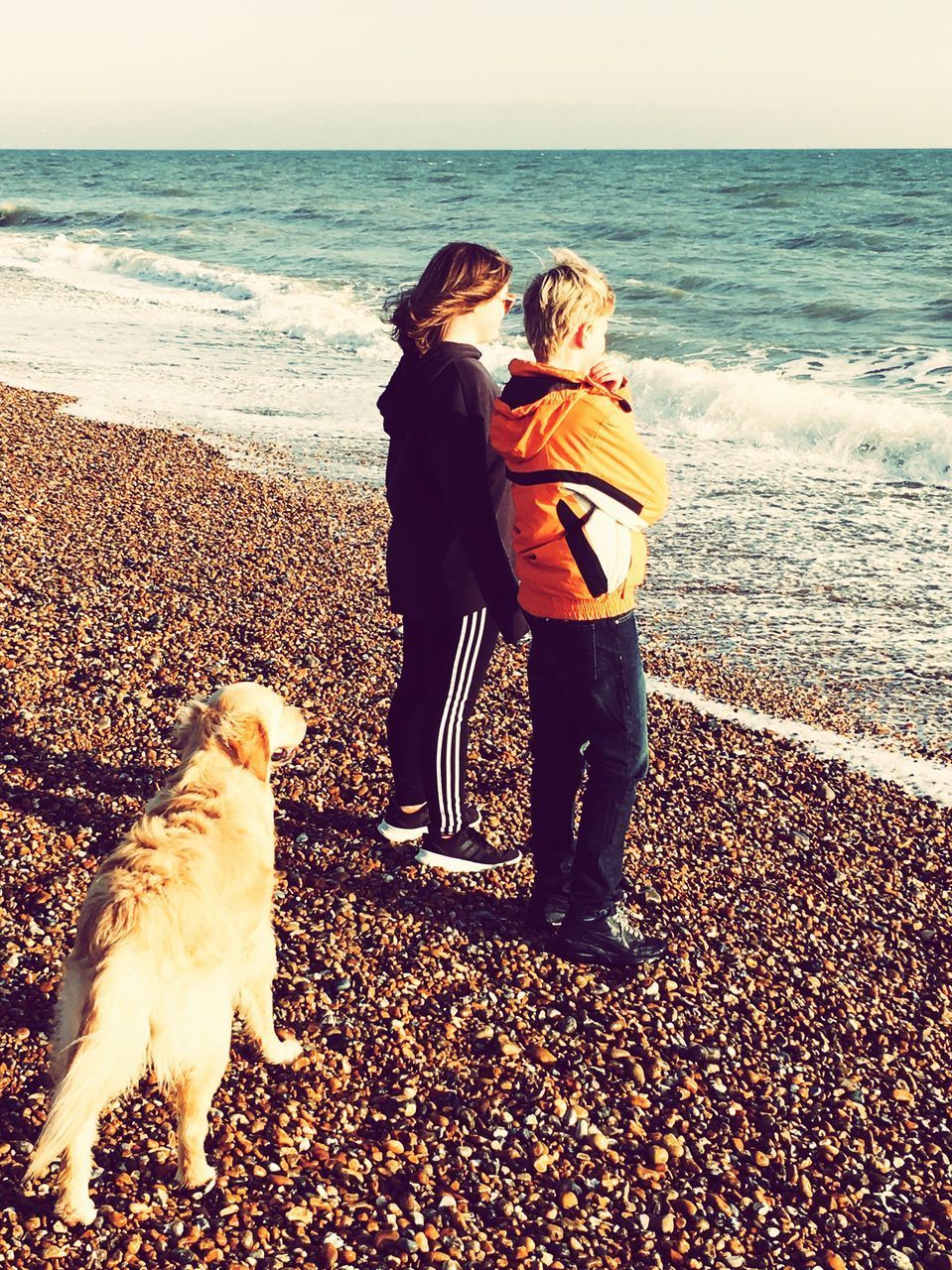 WOMAN WITH DOG STANDING AT BEACH