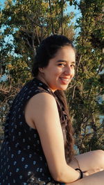 Portrait of a smiling young woman against plants