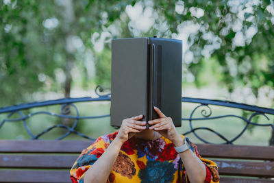 Woman using her laptop as an open book, covering her face