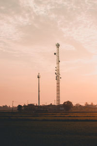 Electricity pylon on field against sky during sunset