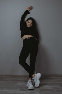 Portrait of young woman standing against wall