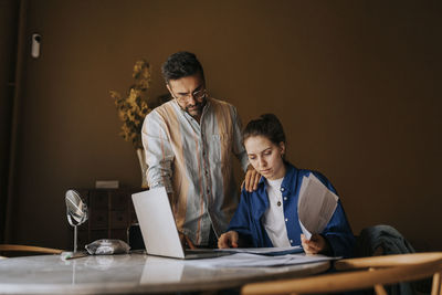 Portrait of young woman using mobile phone while sitting at table