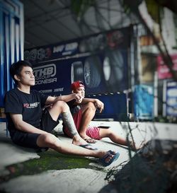 Full length of young men sitting in city