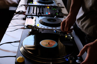 Cropped image of dj playing music from sound mixer at table